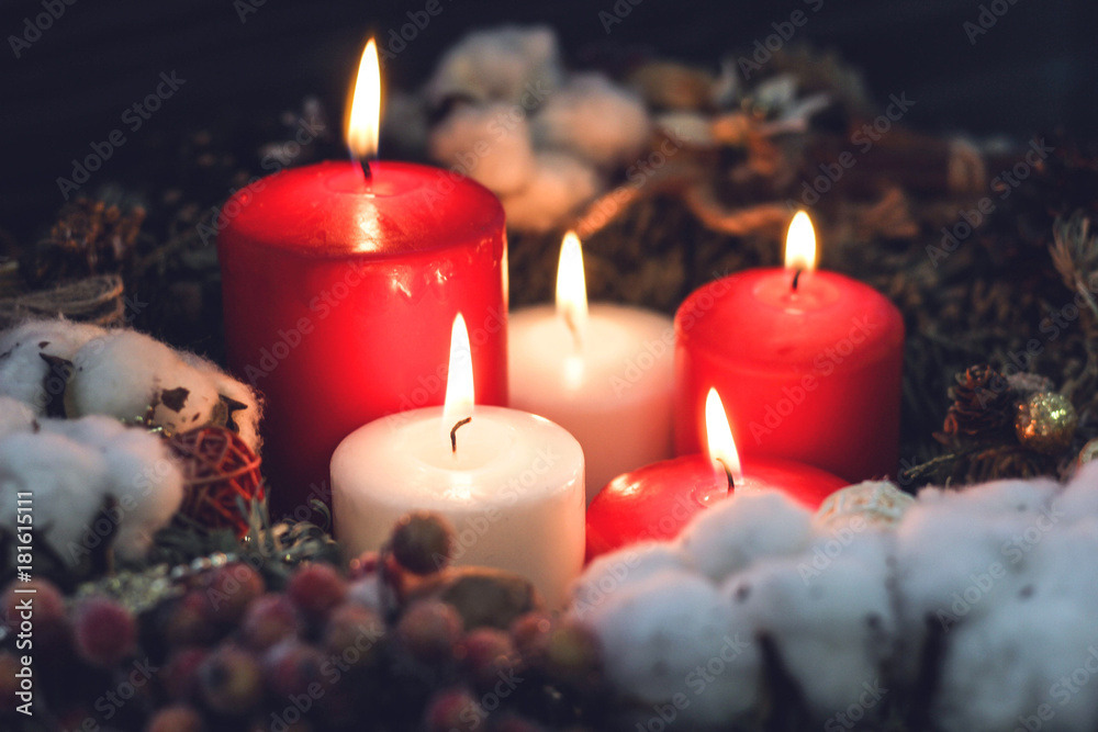 Red and white christmas candles in a pine wreath with natural decorations Red and white christmas candles in a pine wreath with natural decorations