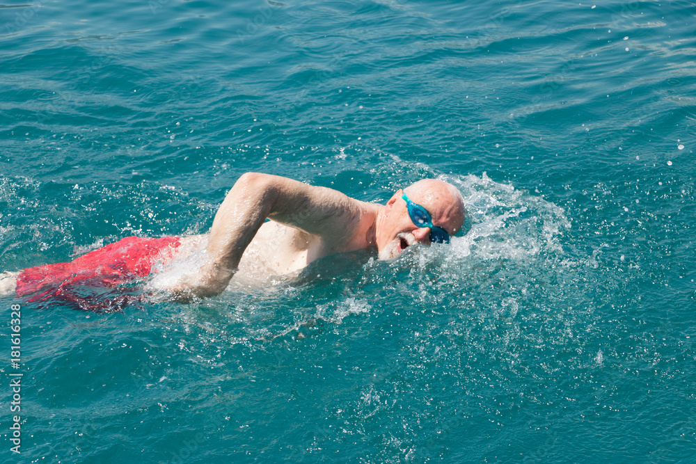 Active swimming. Seventy-year-old man actively swims. Concept: active elderly people.