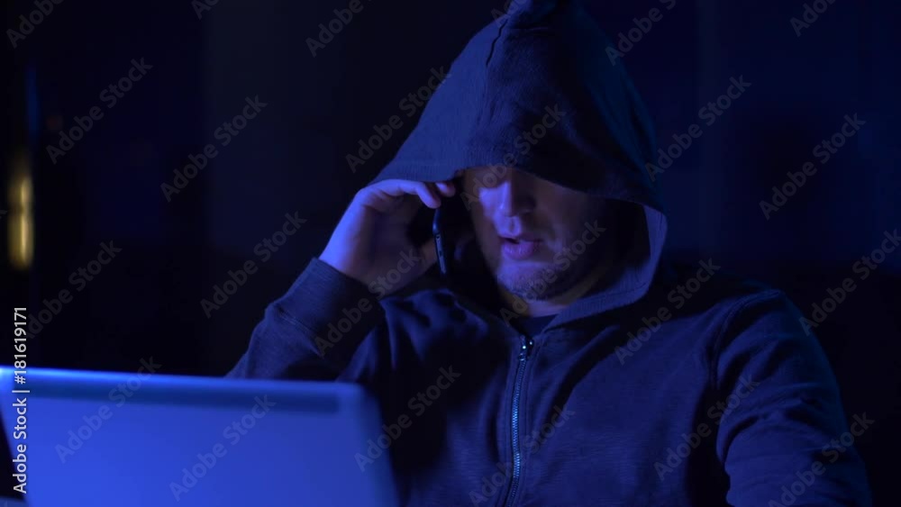 hacker with laptop calling on cellphone