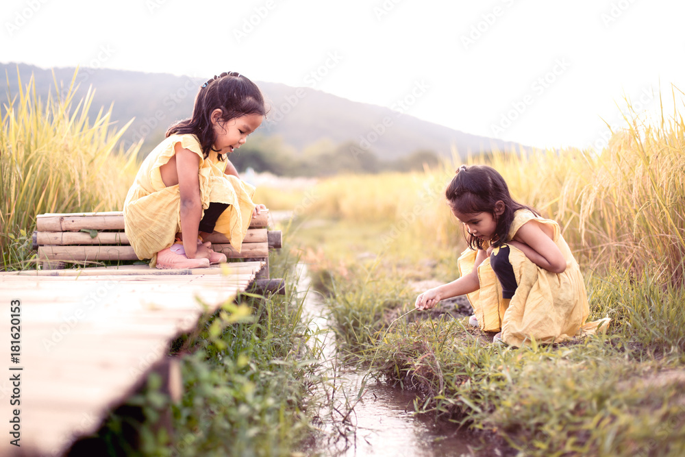 Φωτογραφία Two happy asian little child girls having fun to play together and sitting on ba