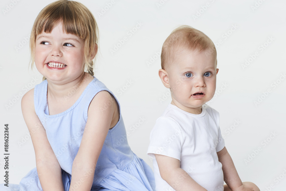 Baby brother and sister in white studio, smiling Baby brother and sister in white studio, smiling