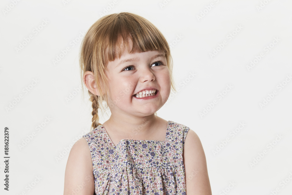 Smiling little girl in white studio, looking away Smiling little girl in white studio, looking away