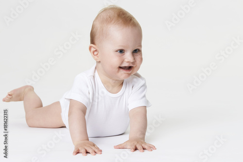 Baby boy in white exploring studio, smiling