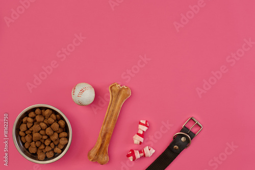 Dog snacks, dog chews, dog bone, ball toy for dog on a pink background with copy space