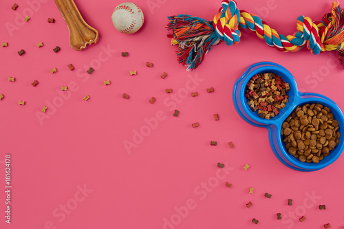 Toys -multi coloured rope, ball, dry food and bone. Accessories for play on pink background top view