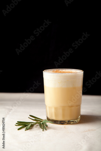 Two glasses with christmas eggnog drink decorated with cinnamon on dark background. Vertical composition. photo