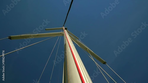 Sailing boats main mast with windex and supporting steel ropes. Shot from start of the mast looking upwards to blue sky. photo