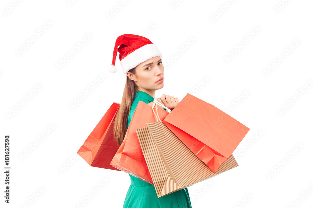 Studio portrait of young woman in Santa hat posing with shopping bags on white background Studio portrait of young woman in Santa hat posing with shopping bags on white background