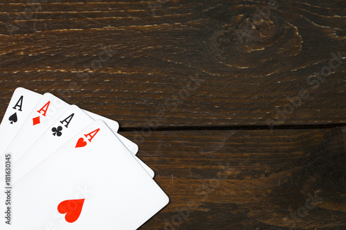 play casino card games on the Brown rough grunge texture of wood table or desk vintage color dark tone style view from top, gang of four aces, hearts on above. Four of a kind of aces poker corner.