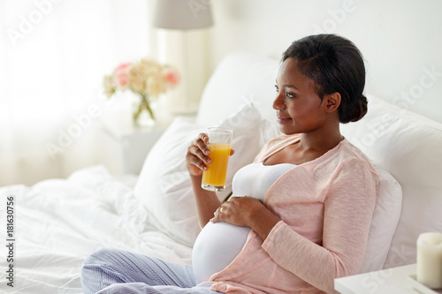 pregnant woman drinking orange juice in bed