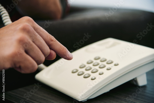 young man dialing on a landline telephone