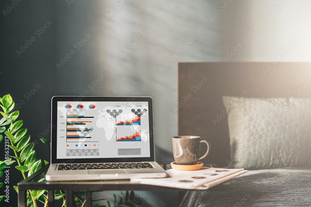 Fototapeta premium Workplace in bad room without people, close-up of laptop with graphs, charts, diagrams on screen on table.Nearby is newspaper, cup of coffee.On background bad, pillow. Mock up.Nobody.Online marketing.