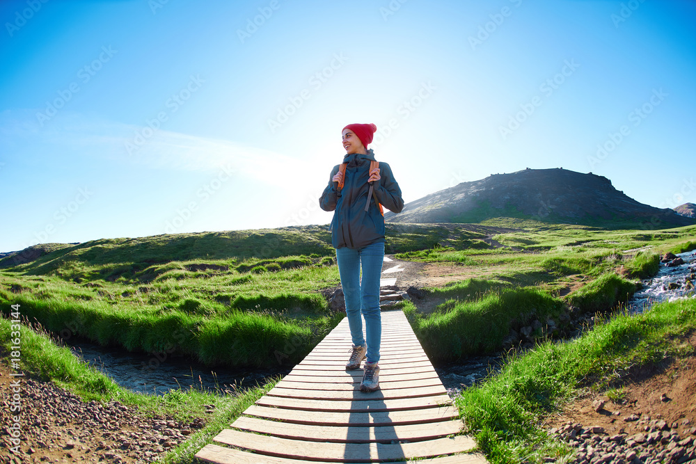 portrait of woman traveler with small orange backpack on a walk in the Valley of the river of Hveragerdi Iceland. Hiking Tour of Reykjadalur Hot Springs