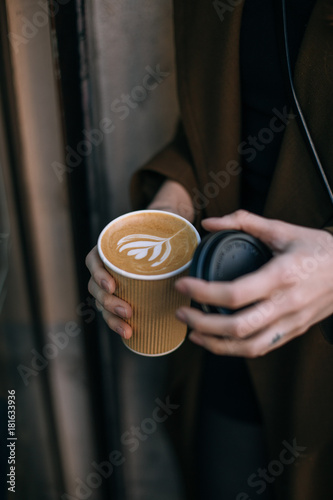 Wallpaper Mural Trendy cool hipster woman or young girl with millennial tribal tattoos on fingers and hands holds take away to go cup of coffee with milk latte art, concept life on the go, warm and cosy drink Torontodigital.ca