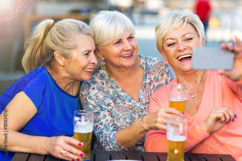 Smiling senior women having a beer in a pub outdoor