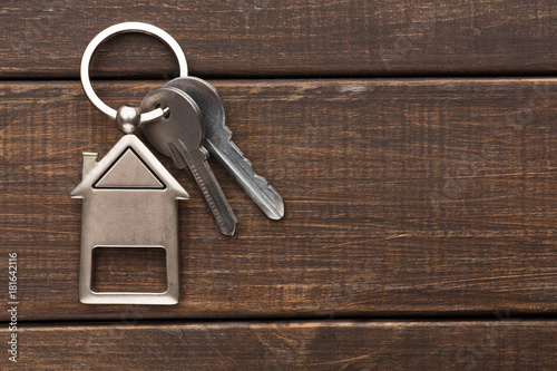 Bunch of keys with house shaped keychain on brown wood photo