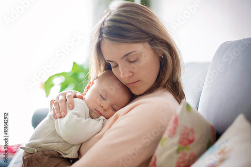 Young mother, holding tenderly her newborn baby boy