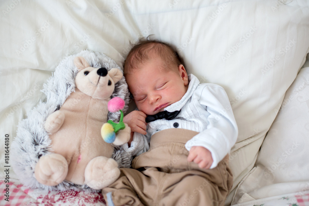 Beautiful little newborn baby boy, dressed as little gentlemen, sleeping in bed