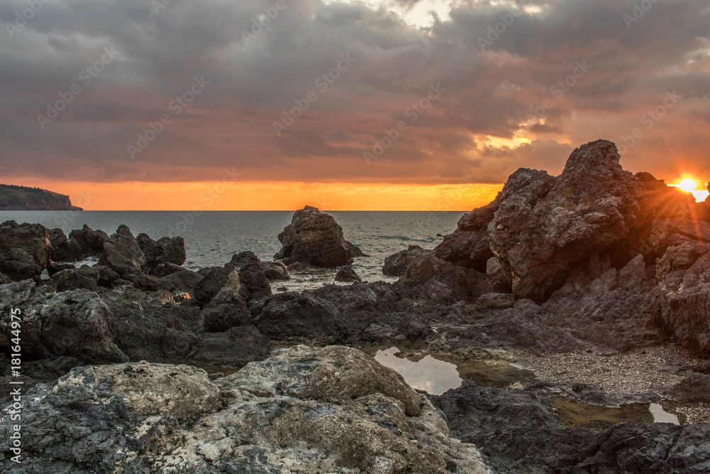 long exposure seascape. Rocks , sunset sky full of colors , sea, sky with clouds , beach. Paesaggio mare al tramonto con bellissimi colori e cielo nuvoloso. Rocce in background