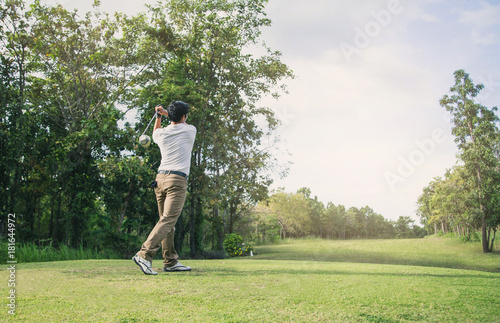 Man playing golf on a golf course in the sun.Golfer hitting golf shot with club on course .