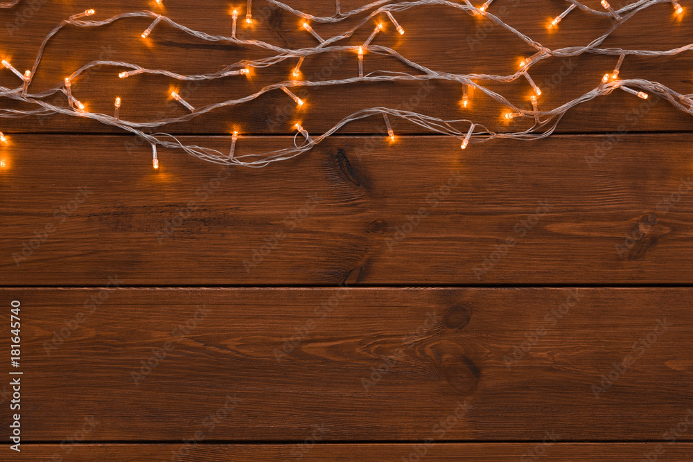 Fototapeta premium Christmas lights border on wood background
