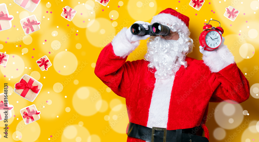 Santa Claus holding binoculars and alarm clock