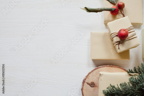 Rustic wrapped boxes with small apples and paper on white, wooden table