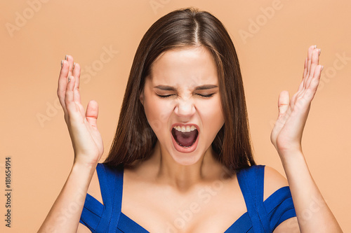 Frustrated young woman screaming at studio