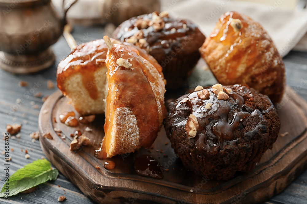 Board with tasty muffins and caramel topping on table Board with tasty muffins and caramel topping on table