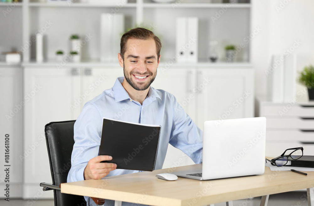 Attractive man with notebook and laptop in office Attractive man with notebook and laptop in office