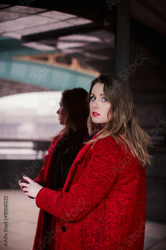 Portrait of young beautiful smiling woman who standing near mirrored window outdoors