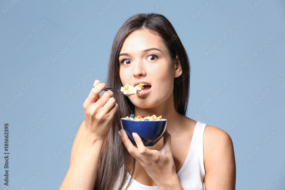 Young woman eating oatmeal on light background Young woman eating oatmeal on light background