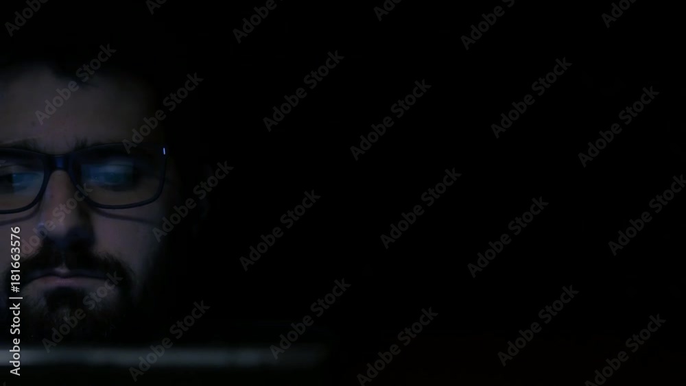 Reveal shot of hacker wearing glasses on laptop
