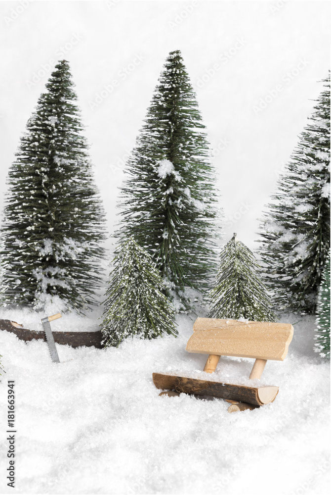 forest winter wonderland with figurines in snow setting forest bench in the foreground and forgotten tree saw in the background snowed in