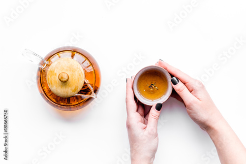 Drink tea. Hand hold cup near tea pot on white background top view copyspace