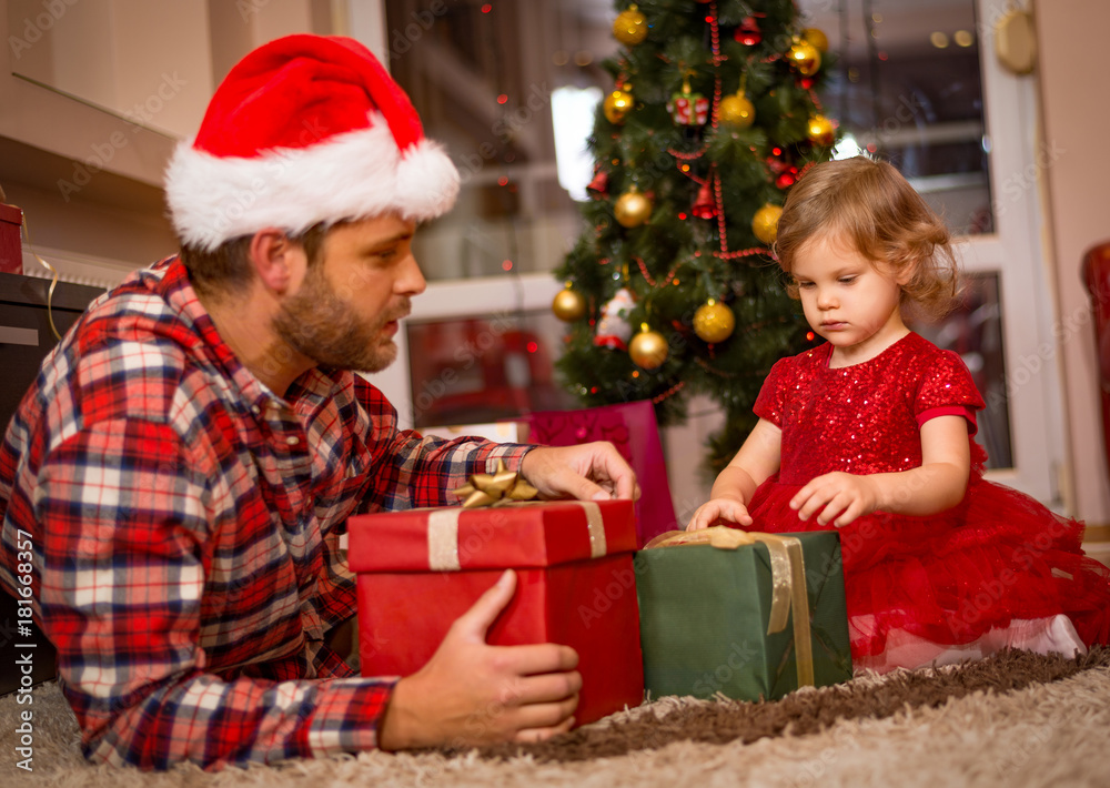 family, christmas, x-mas, happiness and people concept - smiling father and daughter in santa helper hats holding gift box