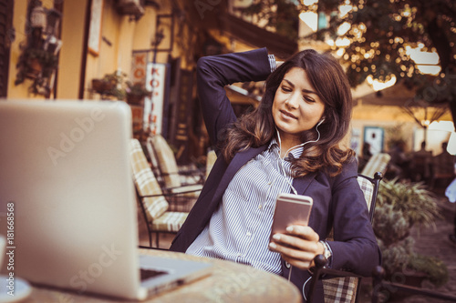 Business woman using smart phone to listening music outside.