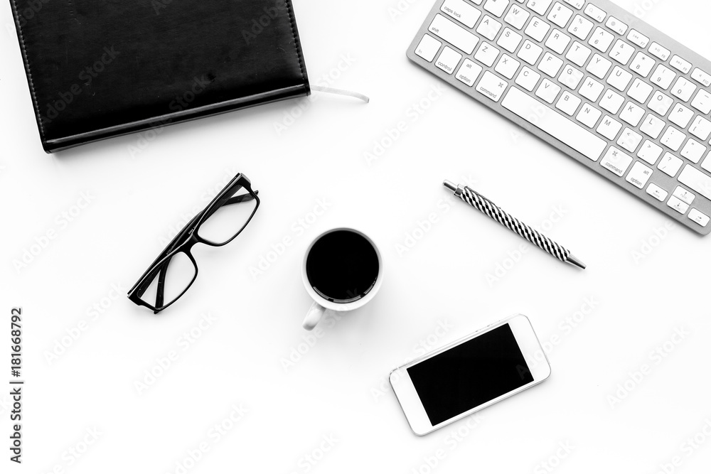 Stylish office desk. Trendy monochrome. Black notebook, glasses, pen, cell phone and coffeee on white background top view Stylish office desk. Trendy monochrome. Black notebook, glasses, pen, cell phone and coffeee on white background top view