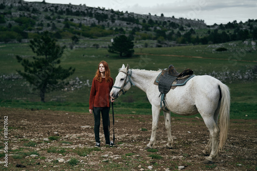 Beautiful young woman on nature walks with horse, in the mountains