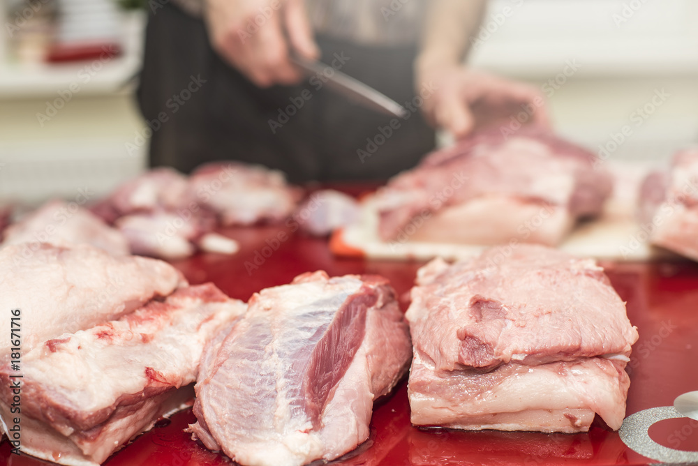 Man slicing pork meat on a table, working process closeup