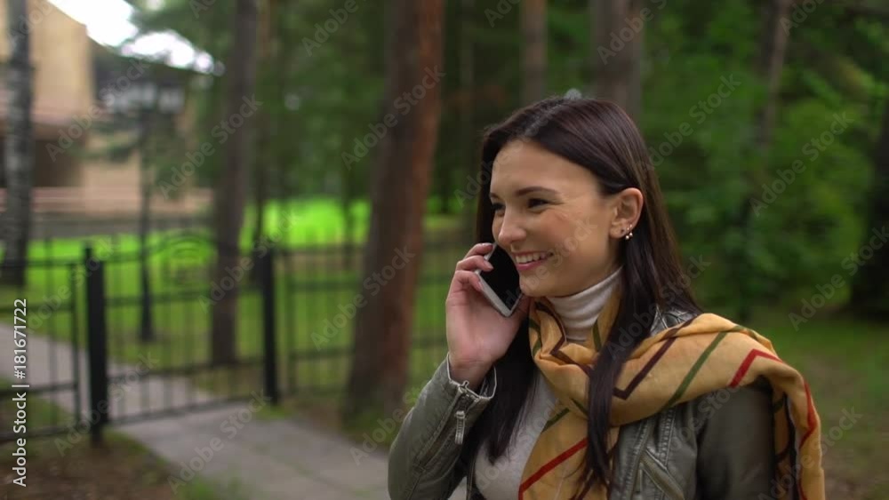 Beautiful young girl is speaking on her mobile phone, outdoor. Portrait of relaxed young woman in a summer park talking on phone. slow-motion Beautiful young girl is speaking on her mobile phone, outdoor. Portrait of relaxed young woman in a summer park talking on phone. slow-motion