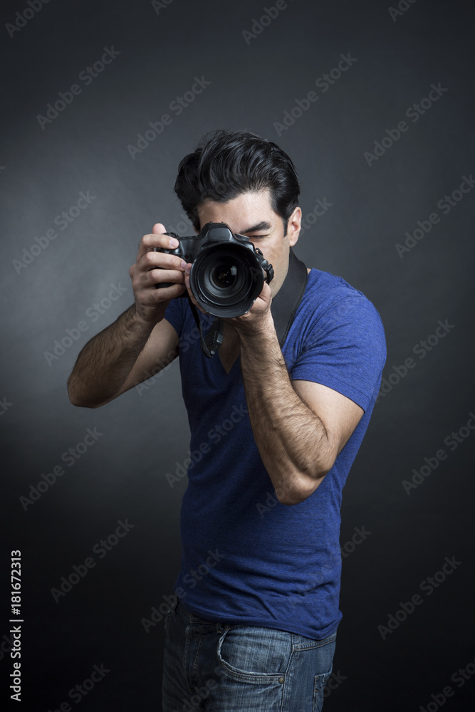 Fototapeta premium fotografo con maglia blu e reflex al collo, scatta una fotografia - sfondo nero