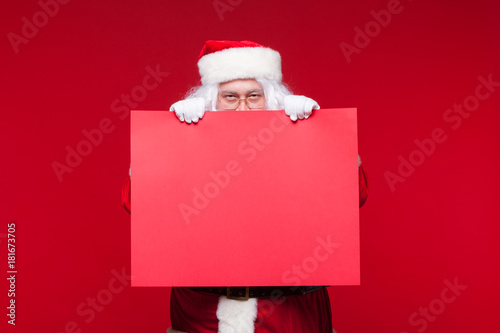 Santa Claus pointing in blank advertisement banner isolated on red background with copy space red leaf © satyrenko