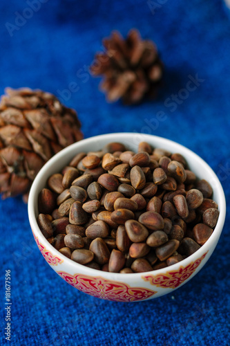 Fresh and ripe pine or cedar nuts in a bowl over blue background.