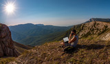 man with laptop, call by cellphone, on beauty mountains landscape