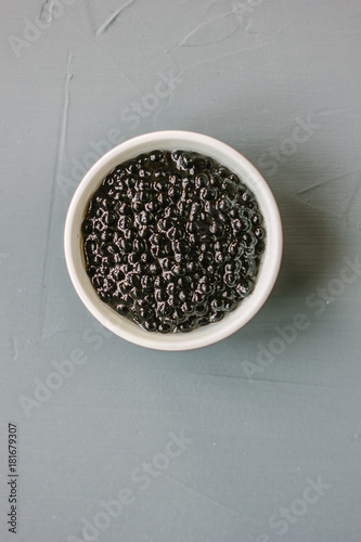 Top view of black caviar in white ceramic bowl. photo