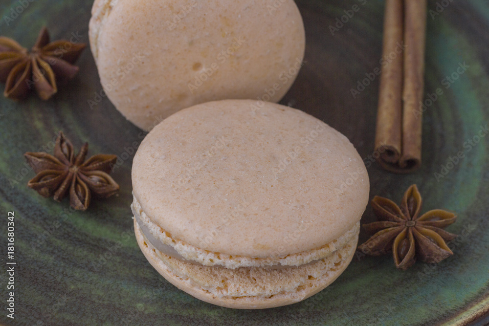 Sweet macarons and anise star on a green background. Close-up. Sweet macarons and anise star on a green background. Close-up.