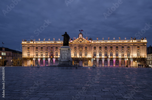 Square Stanislas in Nancy in the evening. In the center stands a monument to Stanislas. In the background there is a Town Hall building.