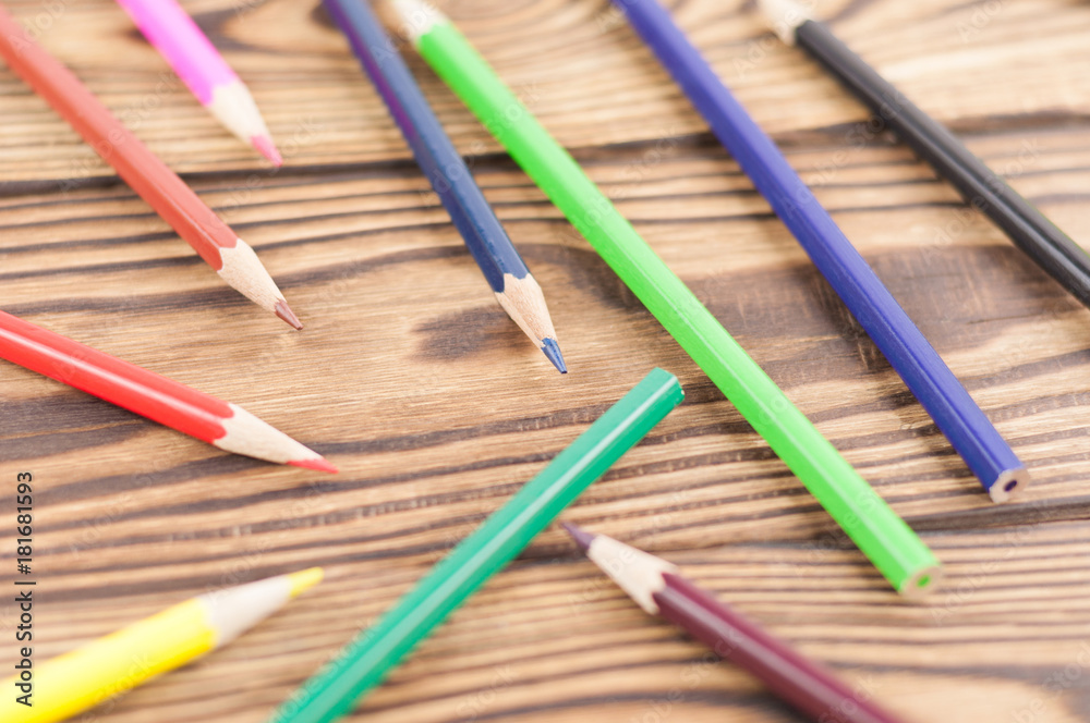 Lot of colored pencils scattered on old brown wooden table Lot of colored pencils scattered on old brown wooden table