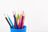 Lot of colored wooden pencils in blue plastic glass on white background